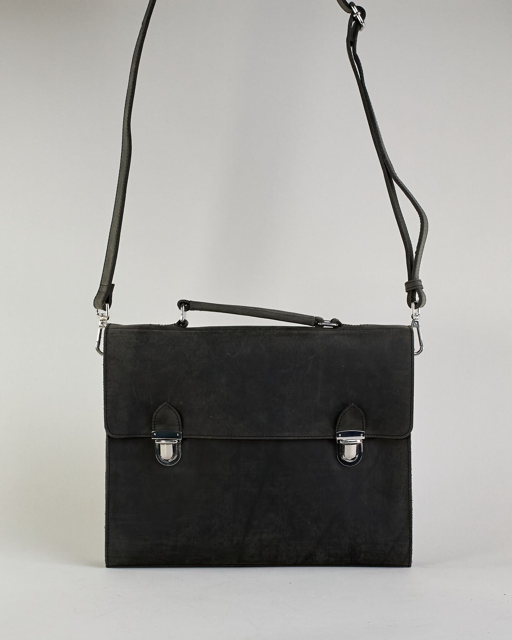Schwarze Aktentasche aus Hunterleder mit Tragegriff, abnehmbarem Schulterriemen, Metallverschlüssen sowie Innenfächer. Das Lederist anfangs matt und entwickelt mit der Zeit eine individuelle Patina. Logo Prägung unter der Lasche mit zwei Metallverschlüssen in klassischem Schultaschen-Stil. #4