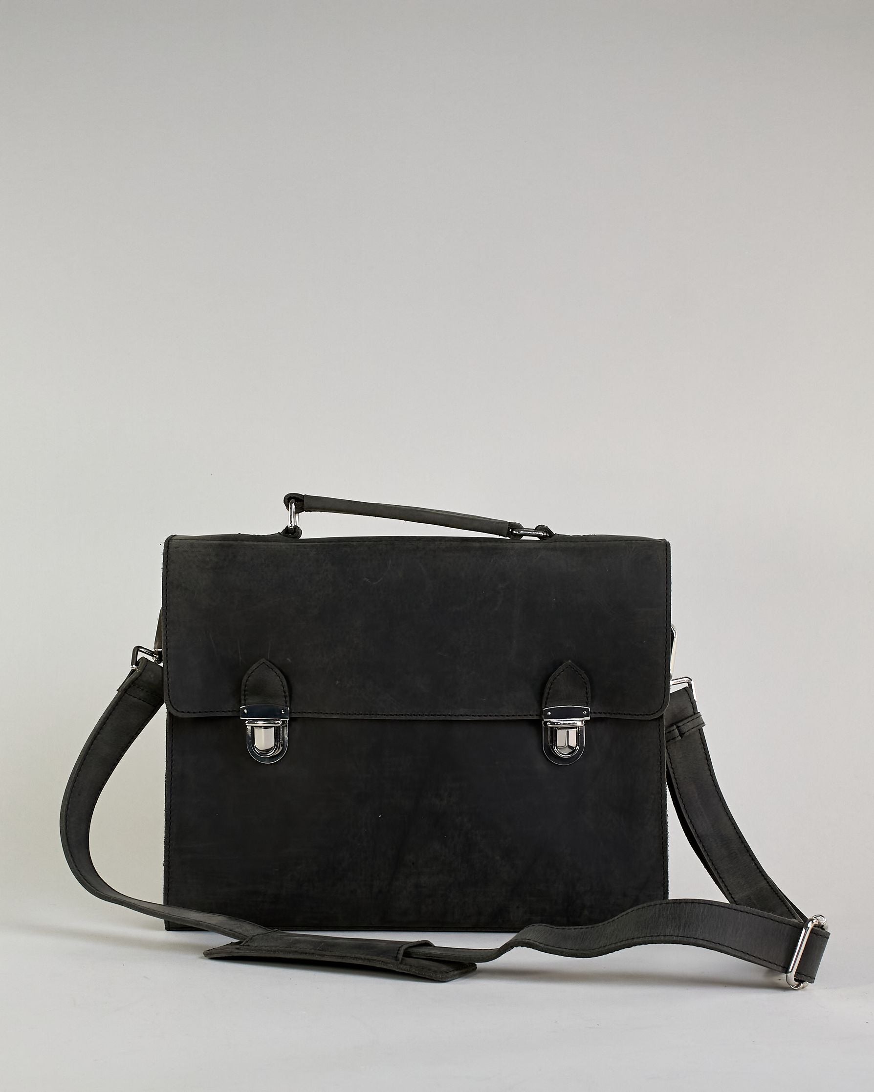Schwarze Aktentasche aus Hunterleder mit Tragegriff, abnehmbarem Schulterriemen, Metallverschlüssen sowie Innenfächer. Das Lederist anfangs matt und entwickelt mit der Zeit eine individuelle Patina. Logo Prägung unter der Lasche mit zwei Metallverschlüssen in klassischem Schultaschen-Stil. #5