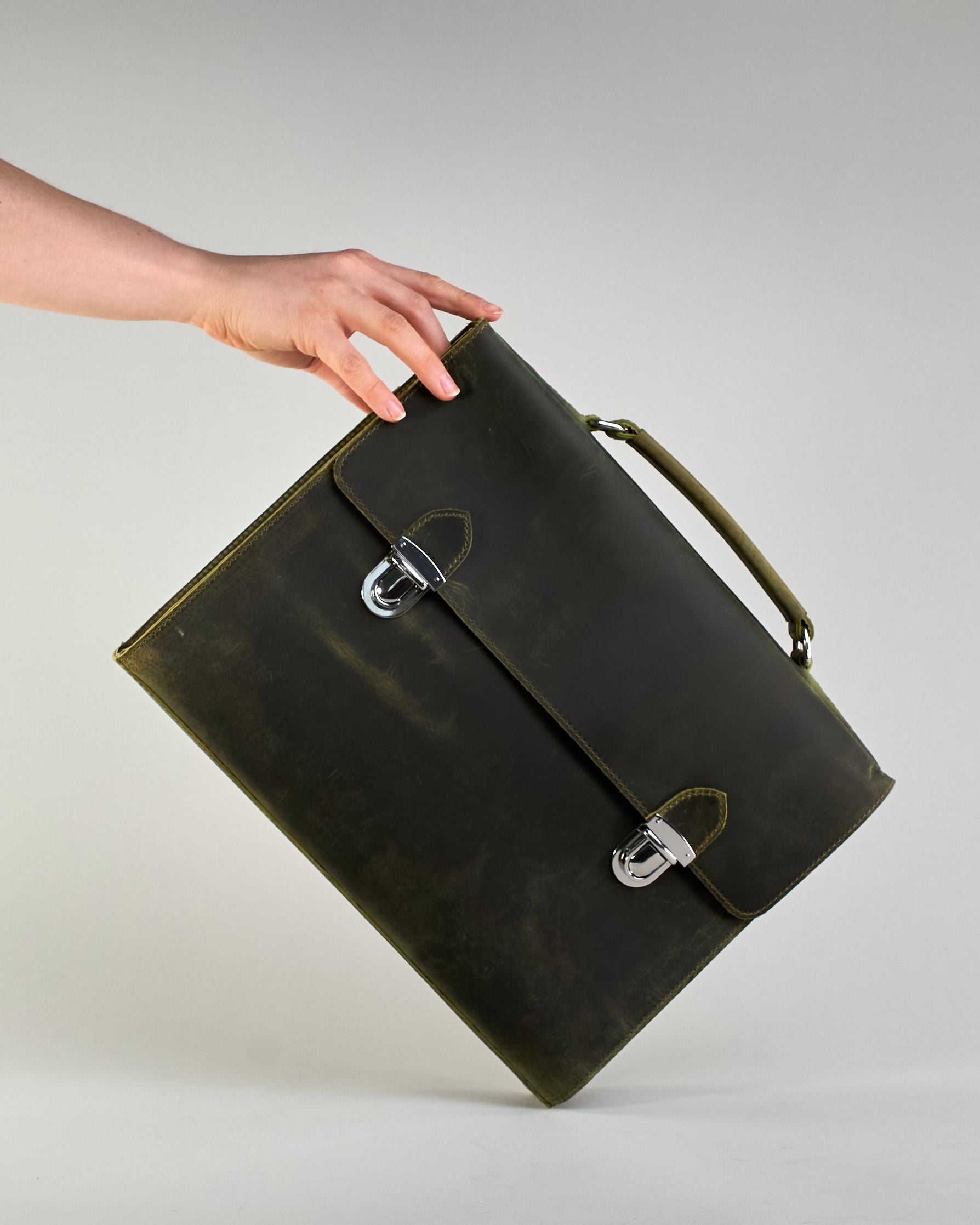 Schwarze Aktentasche aus Hunterleder mit Tragegriff, abnehmbarem Schulterriemen, Metallverschlüssen sowie Innenfächer. Das Lederist anfangs matt und entwickelt mit der Zeit eine individuelle Patina. Logo Prägung unter der Lasche mit zwei Metallverschlüssen in klassischem Schultaschen-Stil. #13