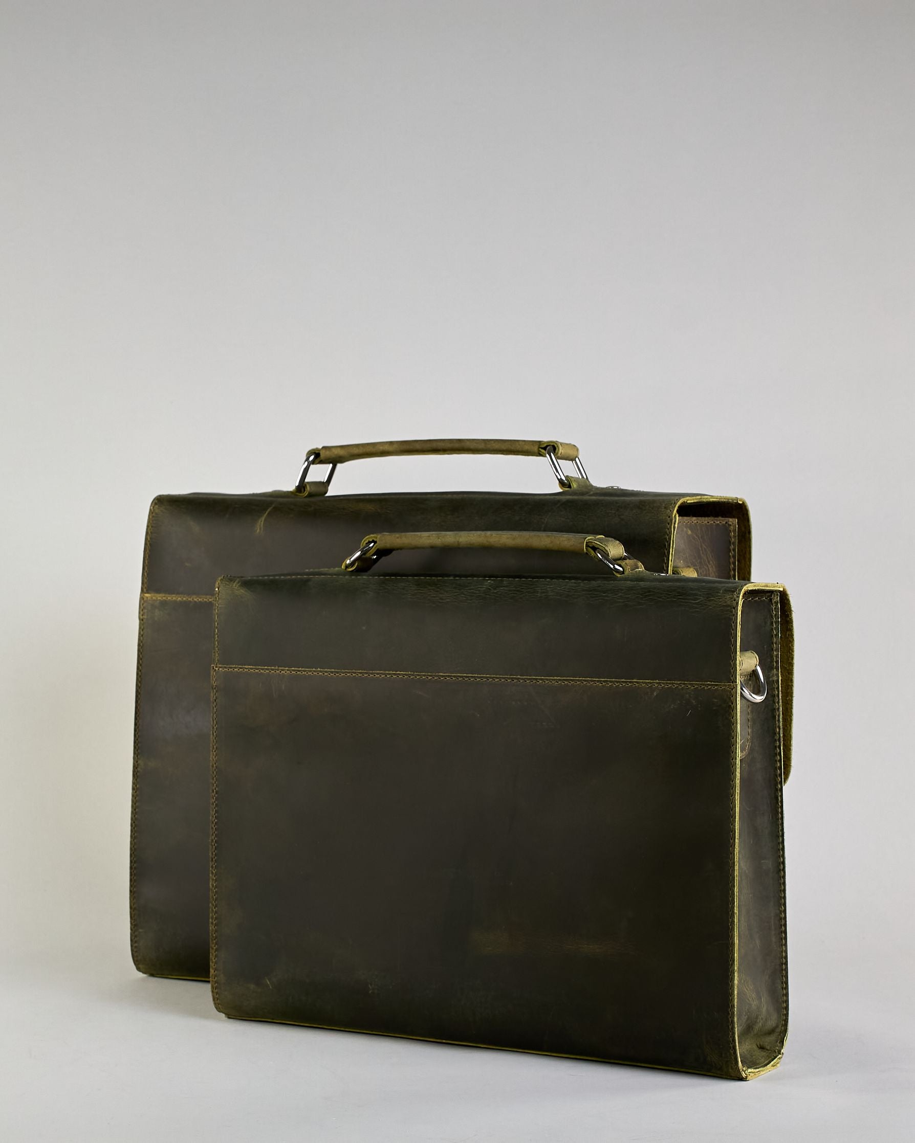 Schwarze Aktentasche aus Hunterleder mit Tragegriff, abnehmbarem Schulterriemen, Metallverschlüssen sowie Innenfächer. Das Lederist anfangs matt und entwickelt mit der Zeit eine individuelle Patina. Logo Prägung unter der Lasche mit zwei Metallverschlüssen in klassischem Schultaschen-Stil. #54