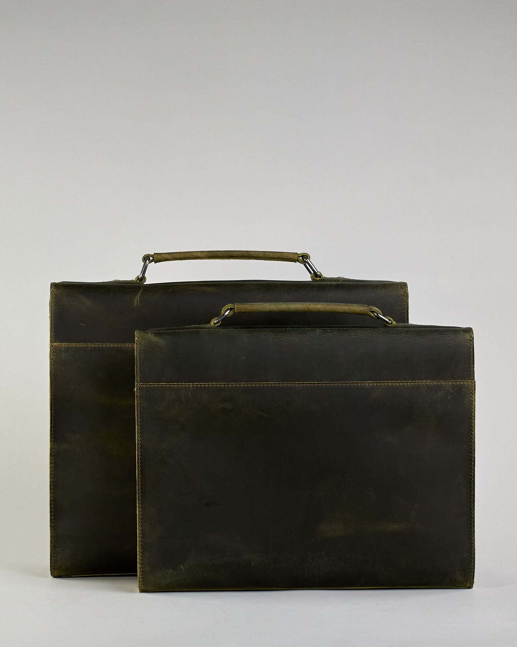 Schwarze Aktentasche aus Hunterleder mit Tragegriff, abnehmbarem Schulterriemen, Metallverschlüssen sowie Innenfächer. Das Lederist anfangs matt und entwickelt mit der Zeit eine individuelle Patina. Logo Prägung unter der Lasche mit zwei Metallverschlüssen in klassischem Schultaschen-Stil. #55