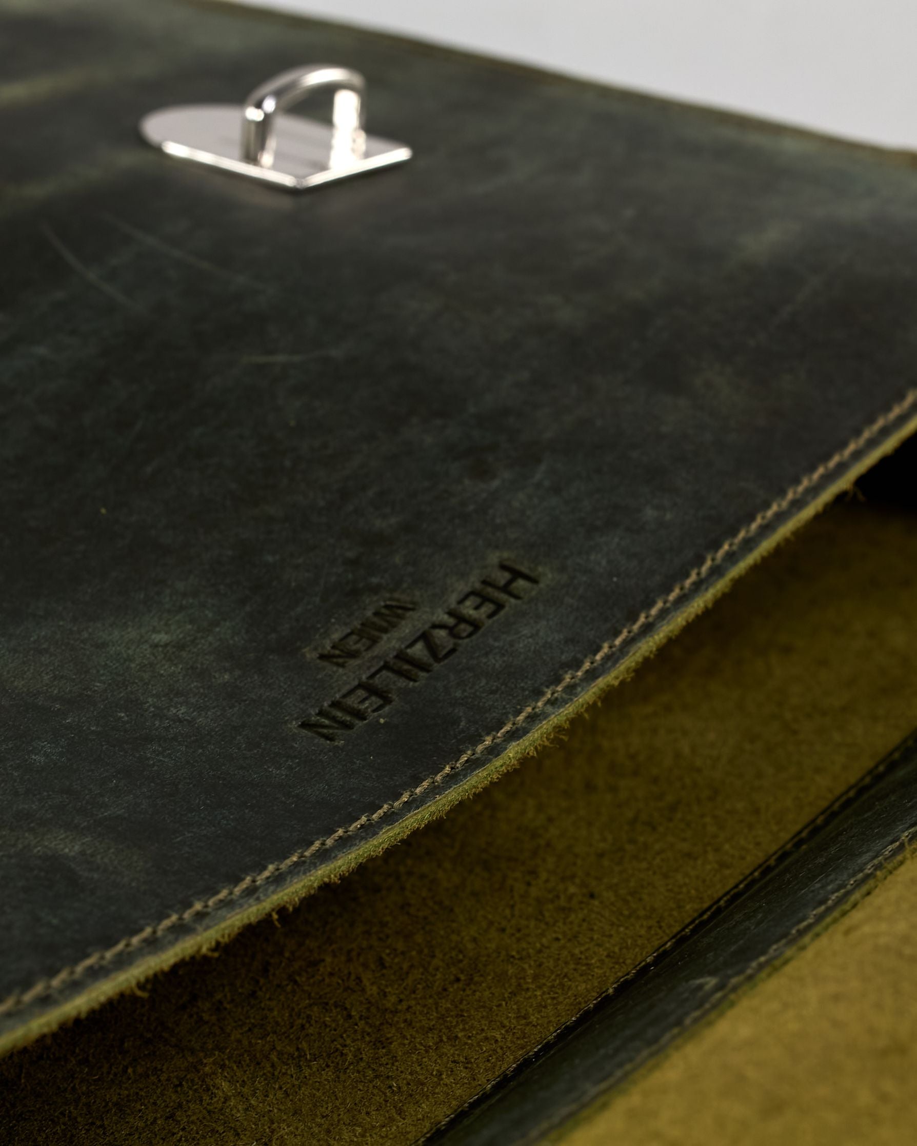 Schwarze Aktentasche aus Hunterleder mit Tragegriff, abnehmbarem Schulterriemen, Metallverschlüssen sowie Innenfächer. Das Lederist anfangs matt und entwickelt mit der Zeit eine individuelle Patina. Logo Prägung unter der Lasche mit zwei Metallverschlüssen in klassischem Schultaschen-Stil. #56