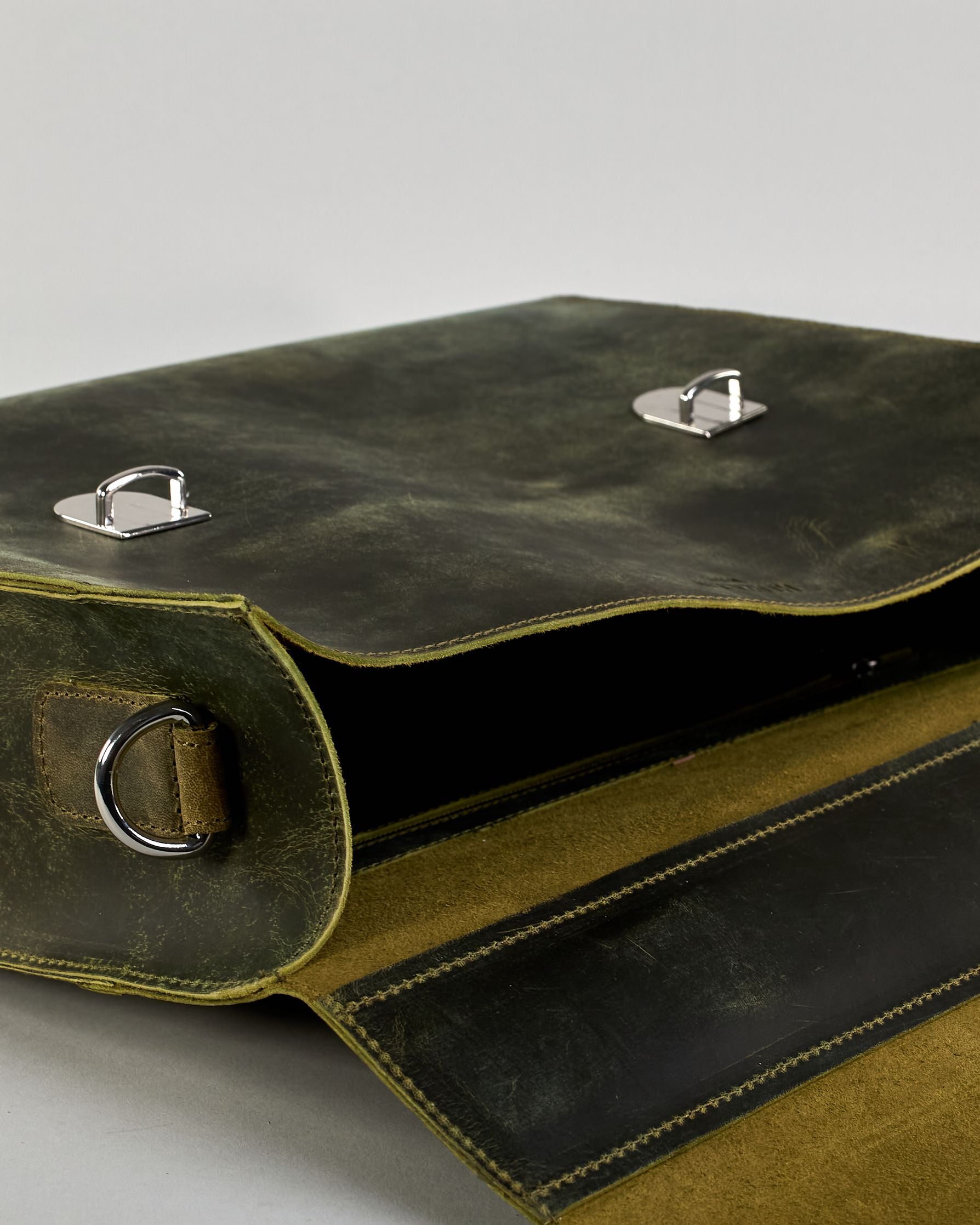 Schwarze Aktentasche aus Hunterleder mit Tragegriff, abnehmbarem Schulterriemen, Metallverschlüssen sowie Innenfächer. Das Lederist anfangs matt und entwickelt mit der Zeit eine individuelle Patina. Logo Prägung unter der Lasche mit zwei Metallverschlüssen in klassischem Schultaschen-Stil. #57