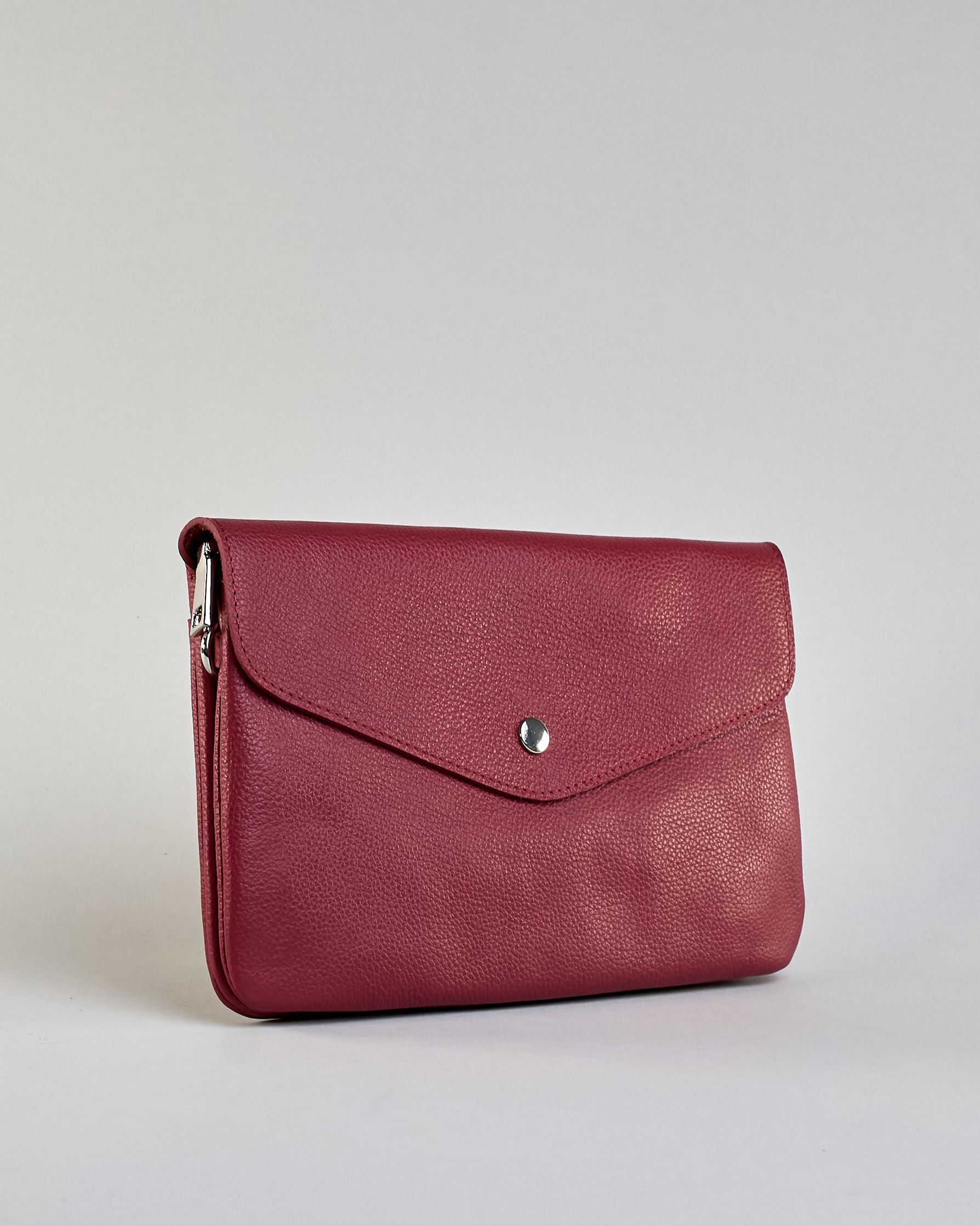 Einfärbige kleine Crossbody-Tasche aus genarbtem Rindleder mit Umschlaglasche und silbernem Druckknopf. Die Tasche enthält innen ein Zippfach, ein offenes Fach sowie ein schmales Zwischenfach. Auf der Rückseite ist eine Logoprägung "Herzilein-Wien" #2