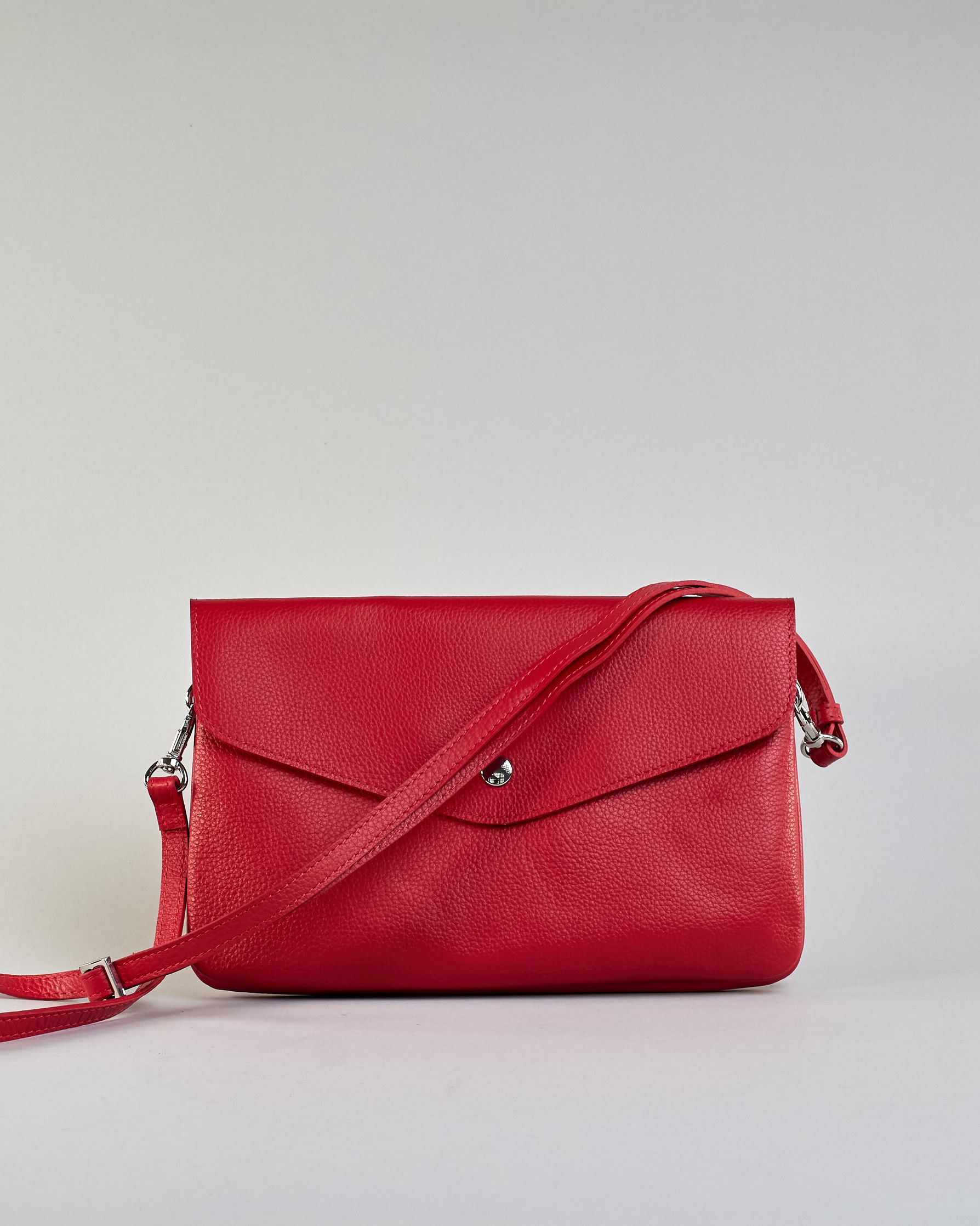 Einfärbige kleine Crossbody-Tasche aus genarbtem Rindleder mit Umschlaglasche und silbernem Druckknopf. Die Tasche enthält innen ein Zippfach, ein offenes Fach sowie ein schmales Zwischenfach. Auf der Rückseite ist eine Logoprägung "Herzilein-Wien" #16