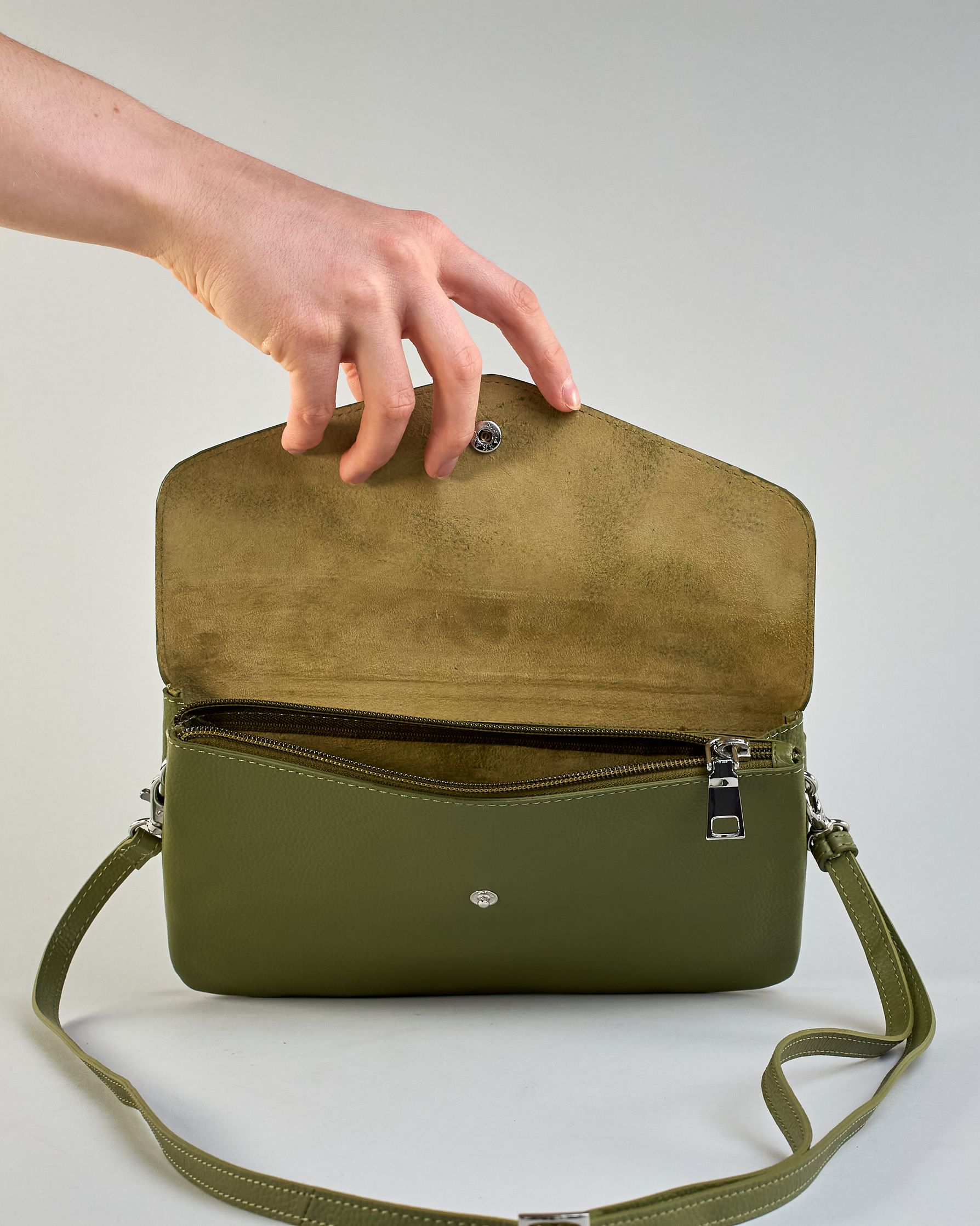 Einfärbige kleine Crossbody-Tasche aus genarbtem Rindleder mit Umschlaglasche und silbernem Druckknopf. Die Tasche enthält innen ein Zippfach, ein offenes Fach sowie ein schmales Zwischenfach. Auf der Rückseite ist eine Logoprägung "Herzilein-Wien" #23