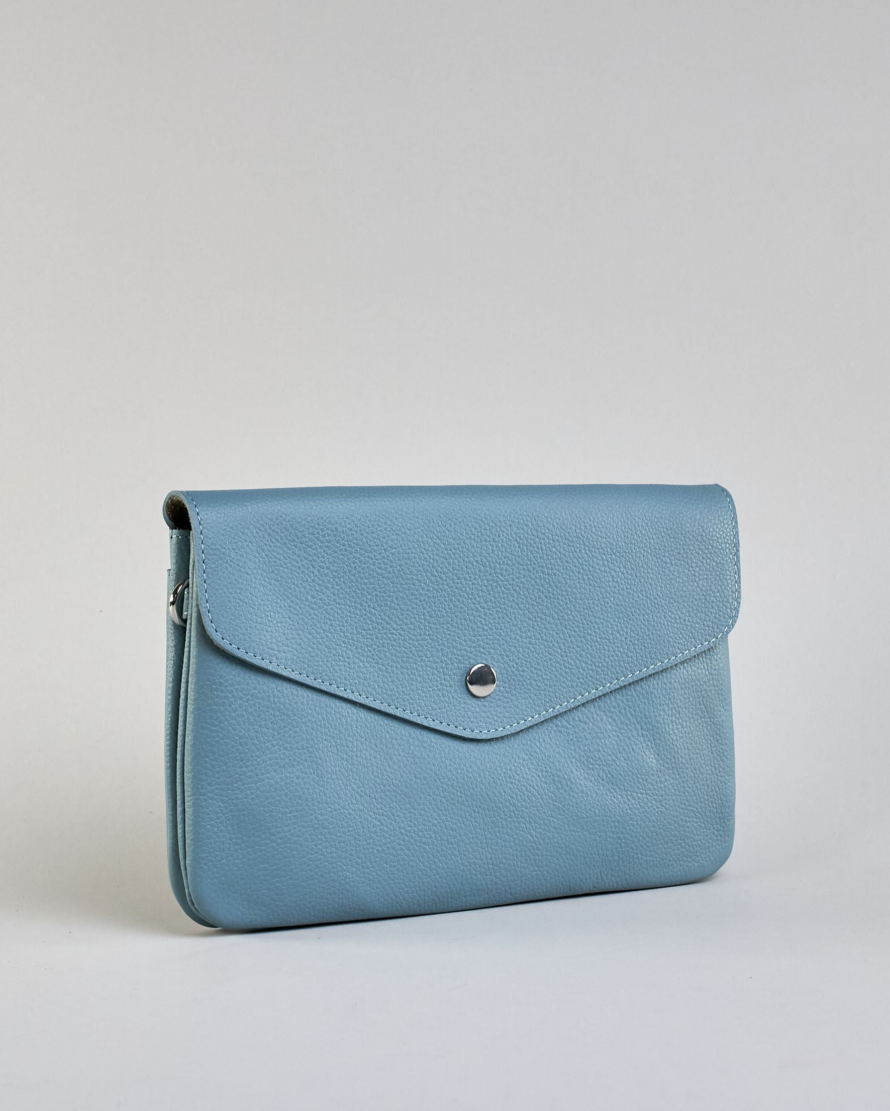 Einfärbige kleine Crossbody-Tasche aus genarbtem Rindleder mit Umschlaglasche und silbernem Druckknopf. Die Tasche enthält innen ein Zippfach, ein offenes Fach sowie ein schmales Zwischenfach. Auf der Rückseite ist eine Logoprägung "Herzilein-Wien" #42