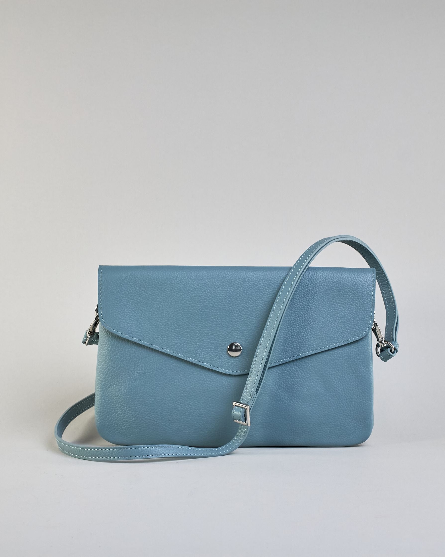Einfärbige kleine Crossbody-Tasche aus genarbtem Rindleder mit Umschlaglasche und silbernem Druckknopf. Die Tasche enthält innen ein Zippfach, ein offenes Fach sowie ein schmales Zwischenfach. Auf der Rückseite ist eine Logoprägung "Herzilein-Wien" #44