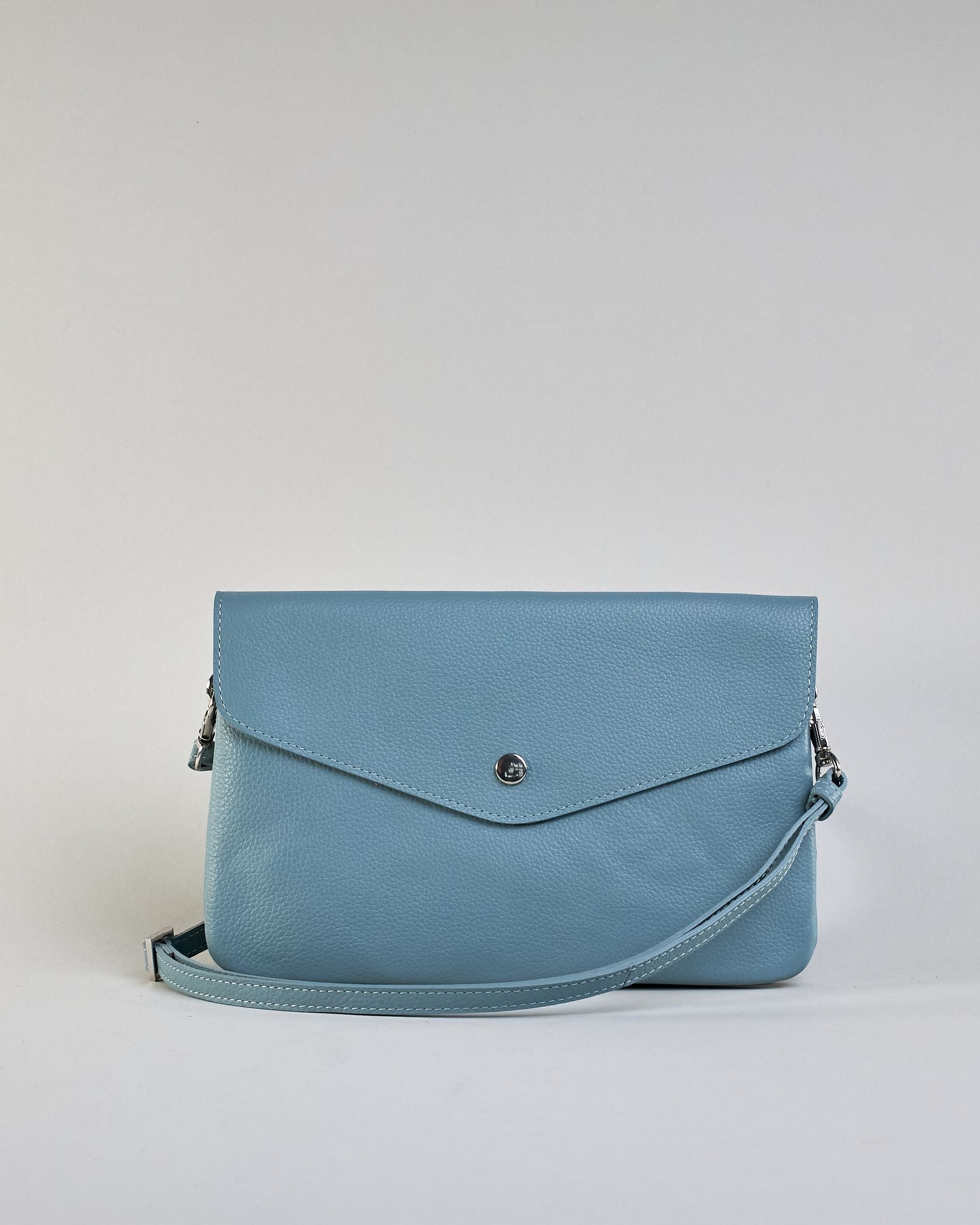 Einfärbige kleine Crossbody-Tasche aus genarbtem Rindleder mit Umschlaglasche und silbernem Druckknopf. Die Tasche enthält innen ein Zippfach, ein offenes Fach sowie ein schmales Zwischenfach. Auf der Rückseite ist eine Logoprägung "Herzilein-Wien" #45