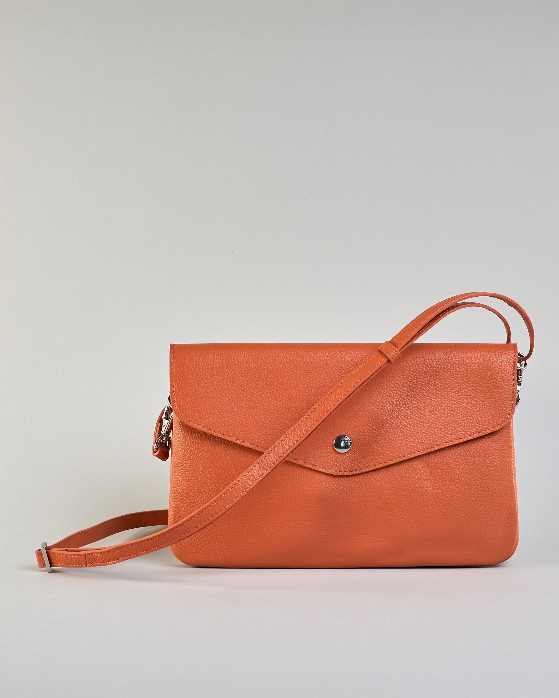 Einfärbige kleine Crossbody-Tasche aus genarbtem Rindleder mit Umschlaglasche und silbernem Druckknopf. Die Tasche enthält innen ein Zippfach, ein offenes Fach sowie ein schmales Zwischenfach. Auf der Rückseite ist eine Logoprägung "Herzilein-Wien" #50