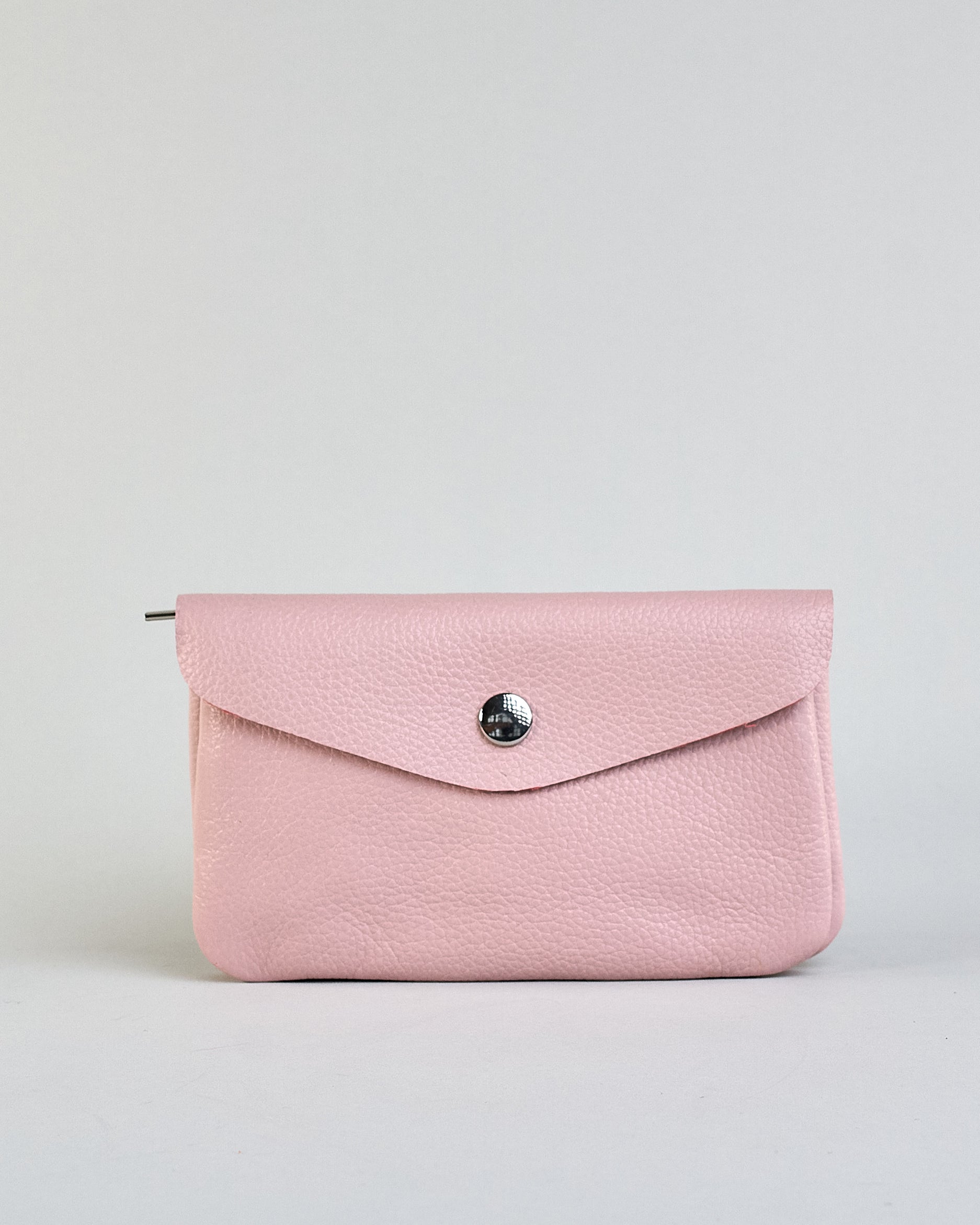 Geldbörse aus genarbtem Rindleder mit Umschlaglasche und silbernem Druckknopf. Die Geldbörse enthält innen ein Zippfach, ein offenes Fach sowie ein schmales Zwischenfach. Auf der Rückseite ist eine Logoprägung "Herzilein-Wien"