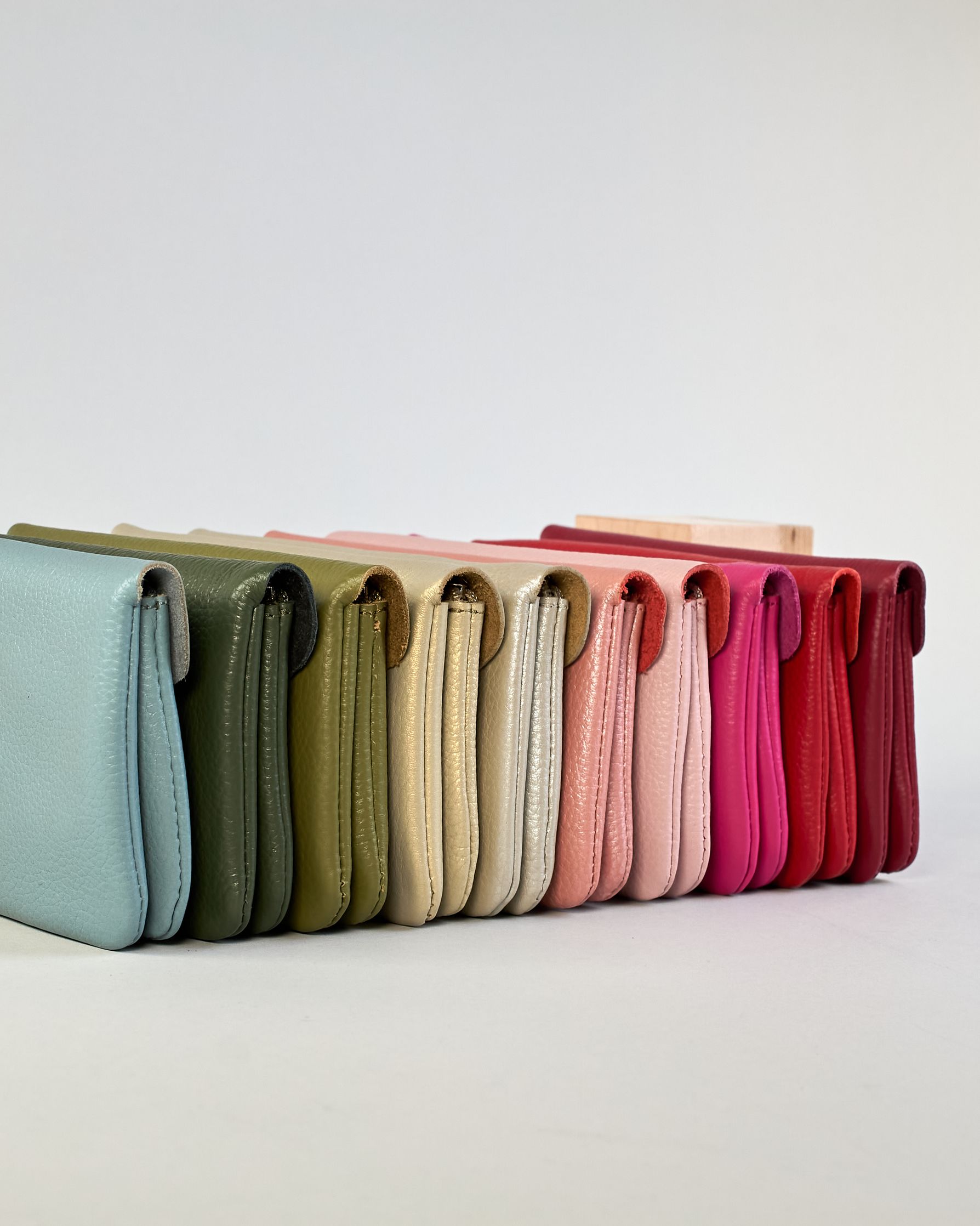 Geldbörse aus genarbtem Rindleder mit Umschlaglasche und silbernem Druckknopf. Die Geldbörse enthält innen ein Zippfach, ein offenes Fach sowie ein schmales Zwischenfach. Auf der Rückseite ist eine Logoprägung "Herzilein-Wien"