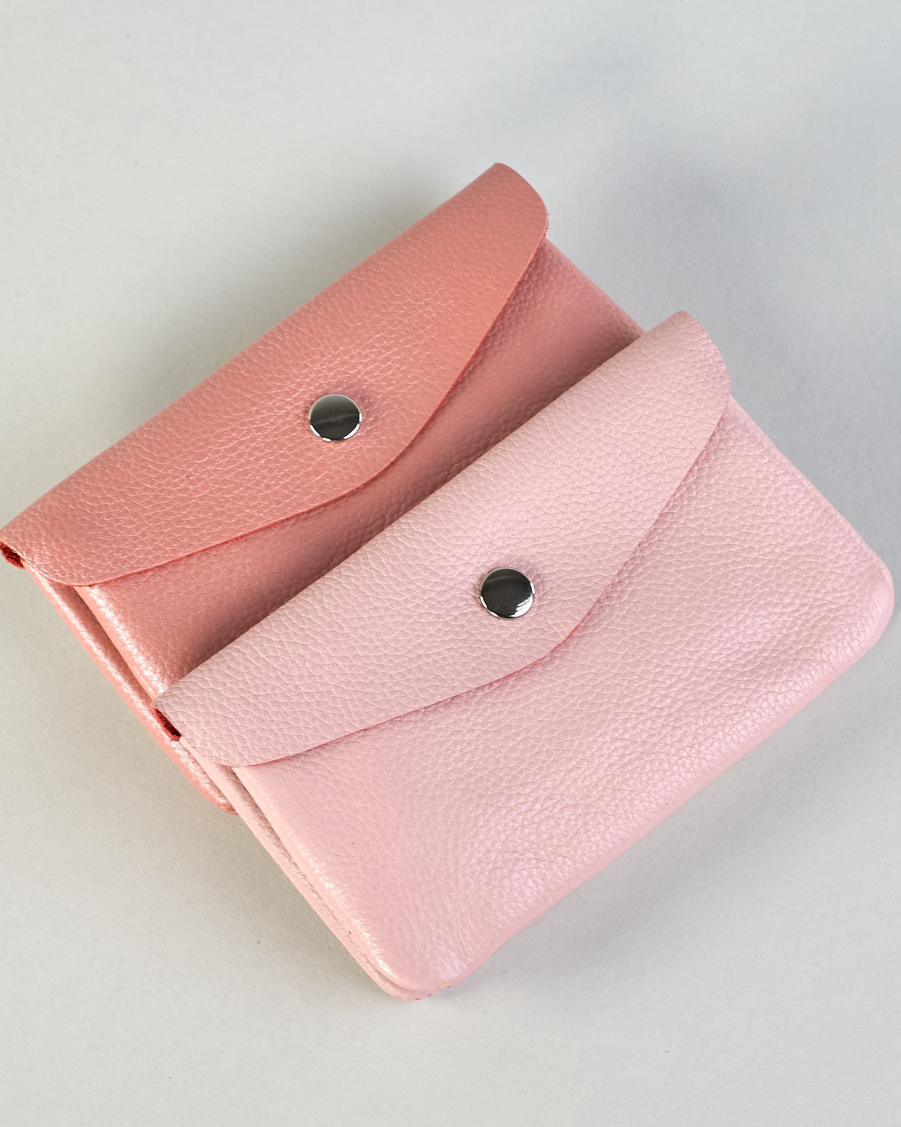 Geldbörse aus genarbtem Rindleder mit Umschlaglasche und silbernem Druckknopf. Die Geldbörse enthält innen ein Zippfach, ein offenes Fach sowie ein schmales Zwischenfach. Auf der Rückseite ist eine Logoprägung "Herzilein-Wien"