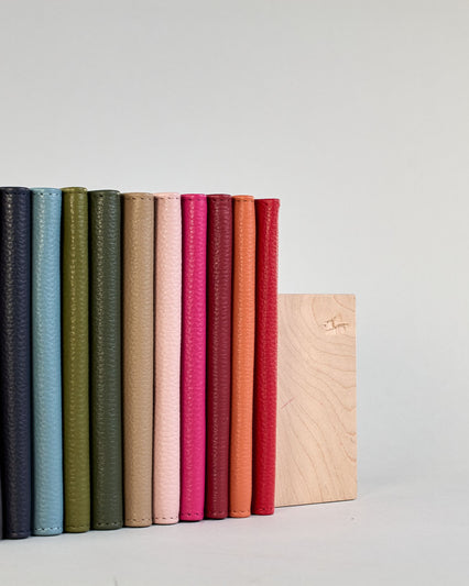 Einfärbige Reisepasshülle aus Leder, innen sind zwei Kartenfächer und ein Schlitz für den Reisepass. Auf der Rückseite ist die Logo Prägung dezent "Herzilein-Wien"