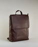 Brauner Rucksack aus Rindleder mit großer Überschlagklappe, verstellbaren Schulterriemen und mehreren Innen- und Außenfächern. Er ist simpel gestaltet und hat nur ein kleines Logo "Herzilein-Wien" unter der Lasche. #2