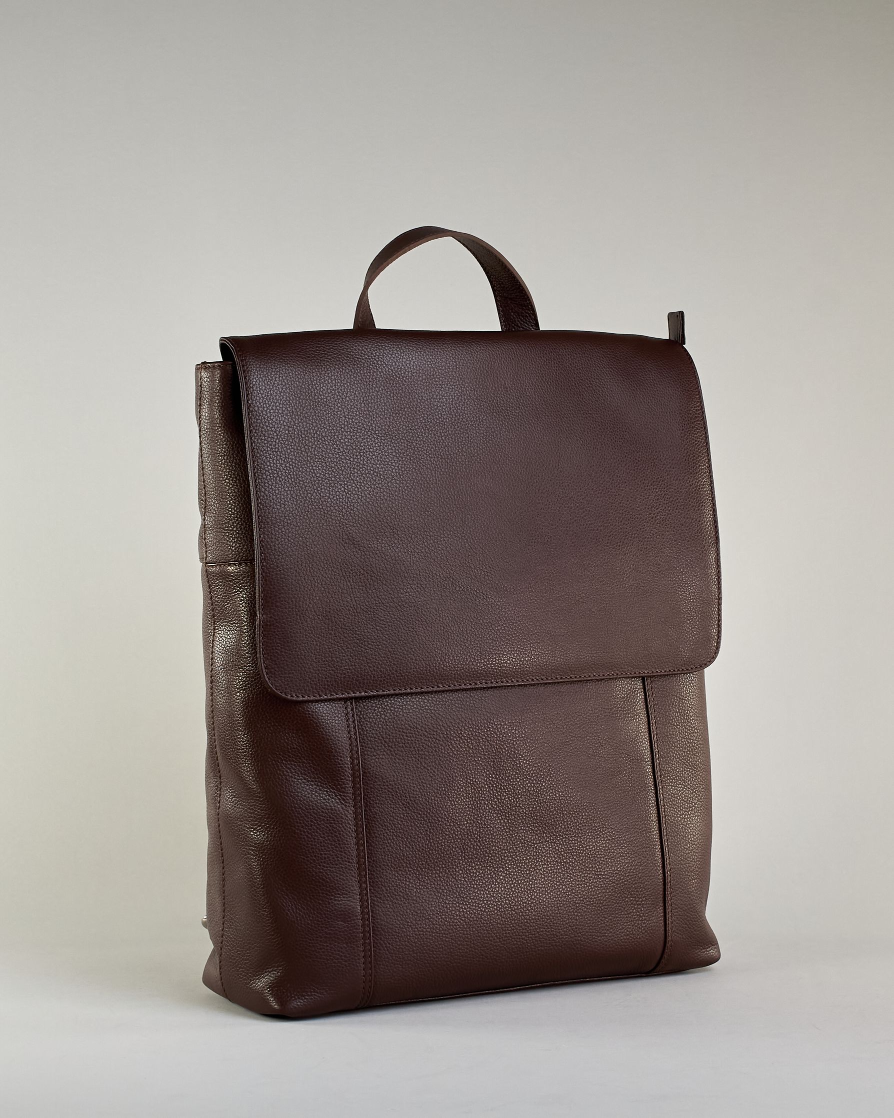 Brauner Rucksack aus Rindleder mit großer Überschlagklappe, verstellbaren Schulterriemen und mehreren Innen- und Außenfächern. Er ist simpel gestaltet und hat nur ein kleines Logo "Herzilein-Wien" unter der Lasche. #4