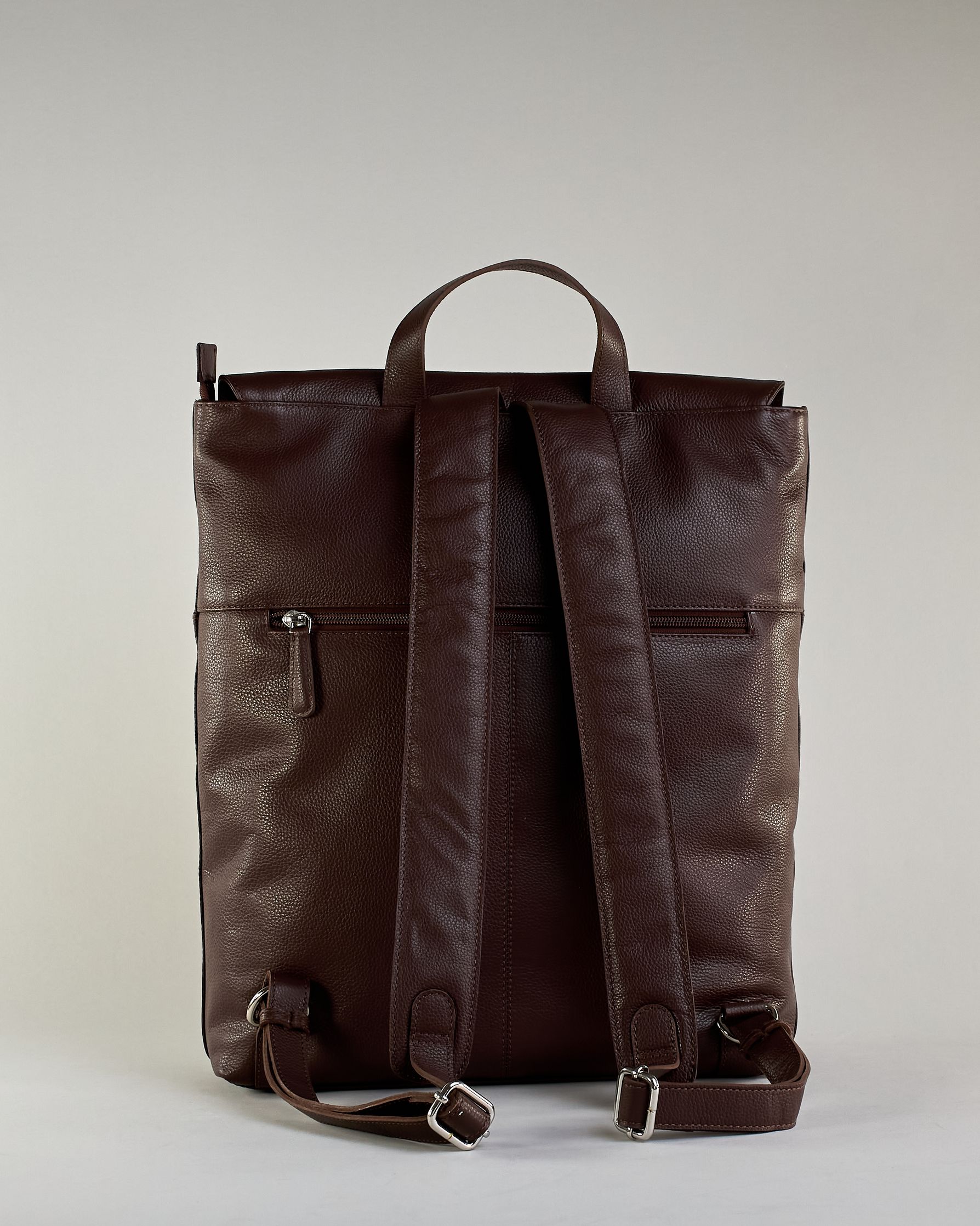 Brauner Rucksack aus Rindleder mit großer Überschlagklappe, verstellbaren Schulterriemen und mehreren Innen- und Außenfächern. Er ist simpel gestaltet und hat nur ein kleines Logo "Herzilein-Wien" unter der Lasche. #5