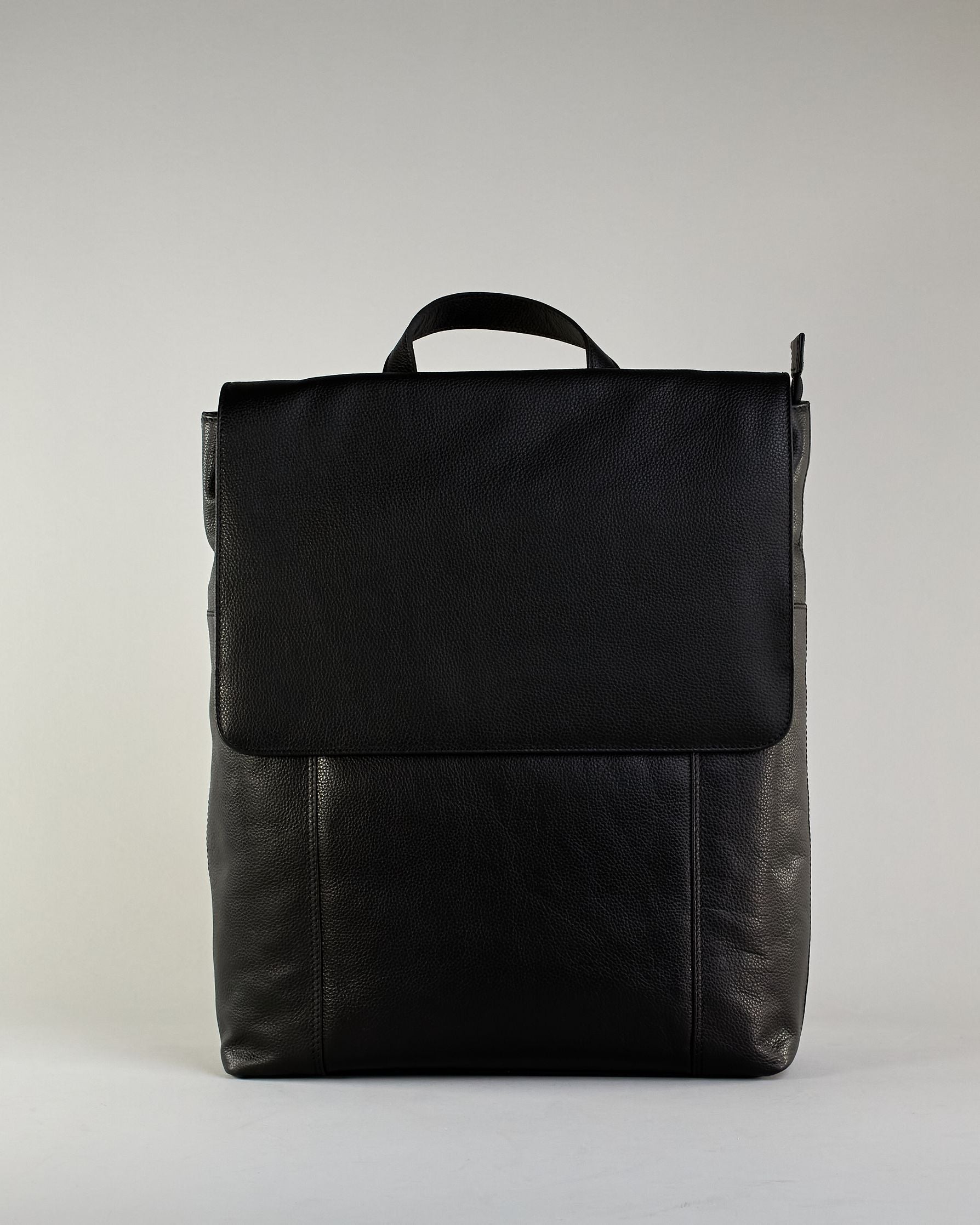 Schwarzer Rucksack aus Rindleder mit großer Überschlagklappe, verstellbaren Schulterriemen und mehreren Innen- und Außenfächern. Er ist simpel gestaltet und hat nur ein kleines Logo "Herzilein-Wien" unter der Lasche. #1