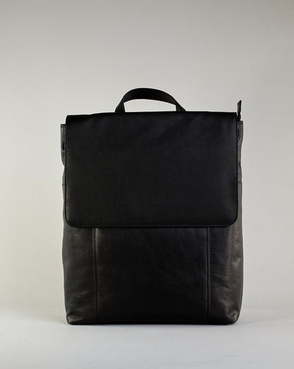Schwarzer Rucksack aus Rindleder mit großer Überschlagklappe, verstellbaren Schulterriemen und mehreren Innen- und Außenfächern. Er ist simpel gestaltet und hat nur ein kleines Logo "Herzilein-Wien" unter der Lasche. #1